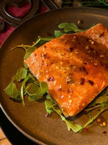 Grilled salmon on cedar plank with maple dijon glaze on a brown plate.