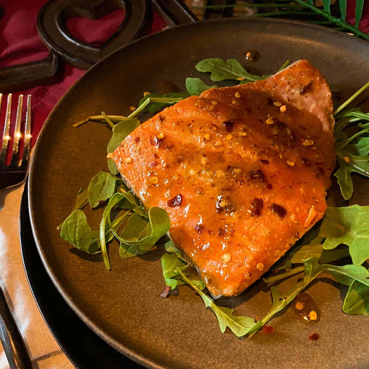 Grilled salmon on cedar plank with maple dijon glaze on a brown plate.