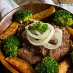 Beef and broccoli with potatoes and onions in a wooden bowl.