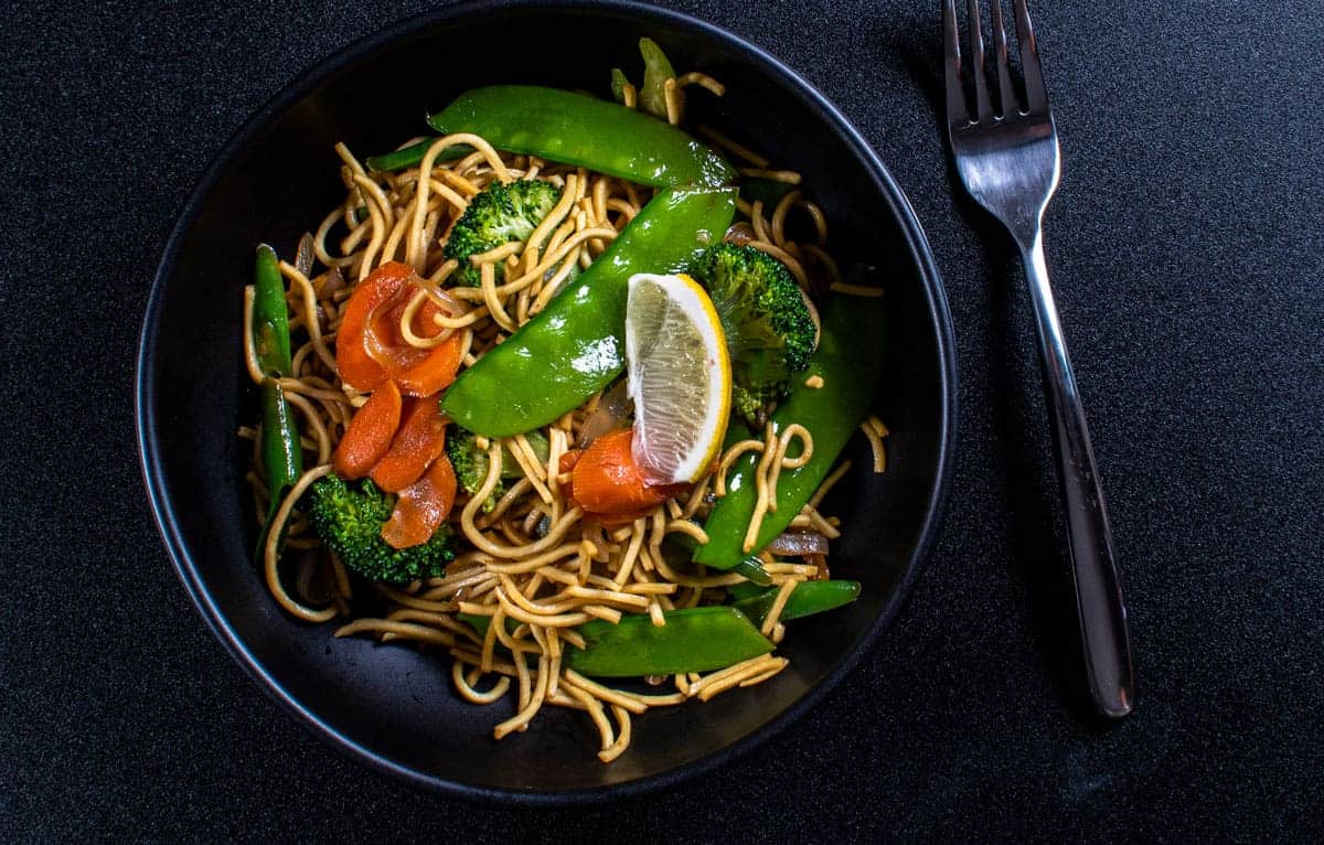 Filipino Vegetable Pancit in a black bowl with a fork.