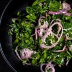 Parsley salad, with shallots, capers, and coarse on a black bowl.