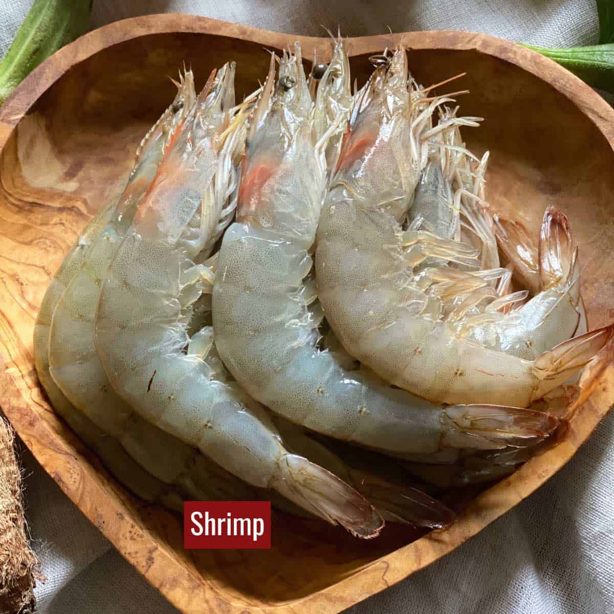 Raw shrimp on a wooden heart shaped dish.