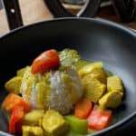 Closeup of Filipino Chicken Curry with Vegetables in a black bowl.