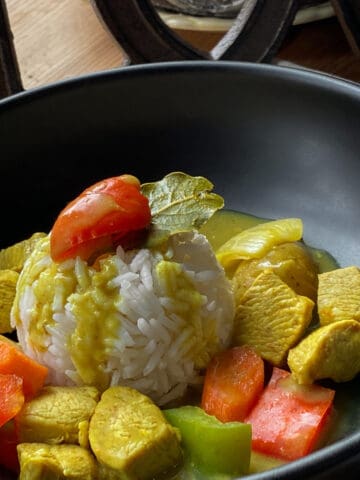 Closeup of Filipino Chicken Curry with Vegetables in a black bowl.
