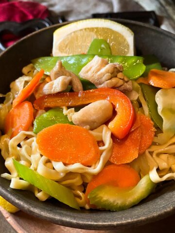 Pancit Guisado egg noodles with chicken bits and vegetables in a bowl.