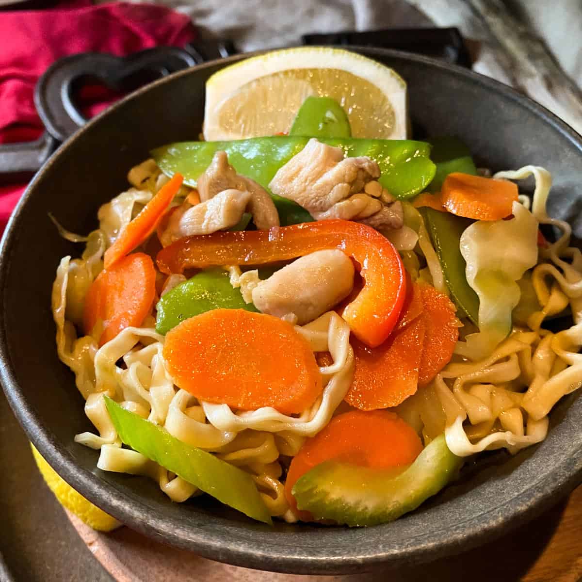 Pancit Guisado egg noodles with chicken bits and vegetables in a bowl.