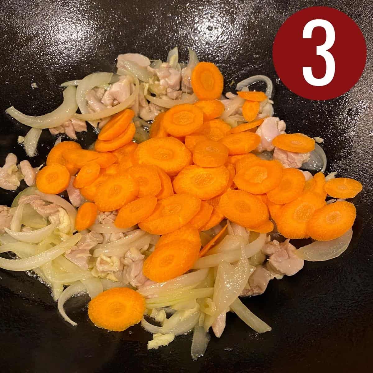 Carrots with chicken, garlic, and onion with oil in a skillet.