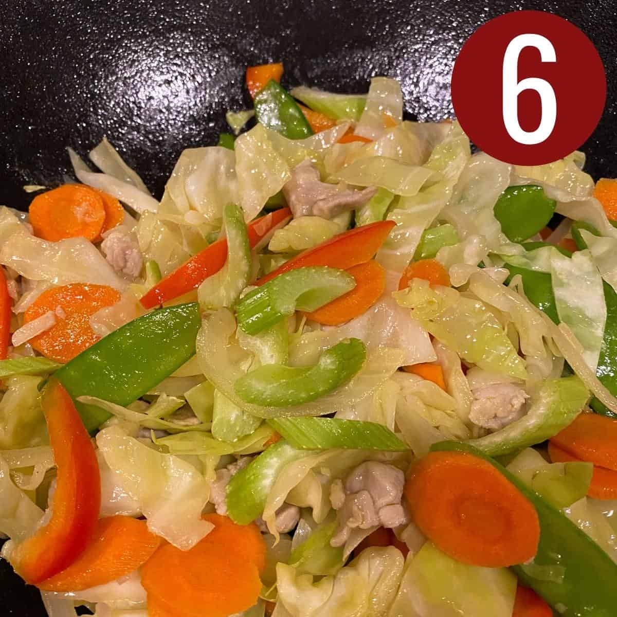 Celery, bell pepper, cabbage, peapods, carrots with chicken, garlic, and onion with oil in a skillet.