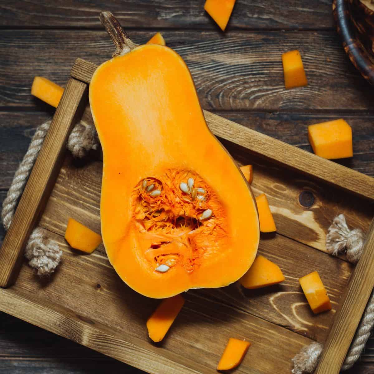 Sliced butternut squash with seed on a wooden tray.