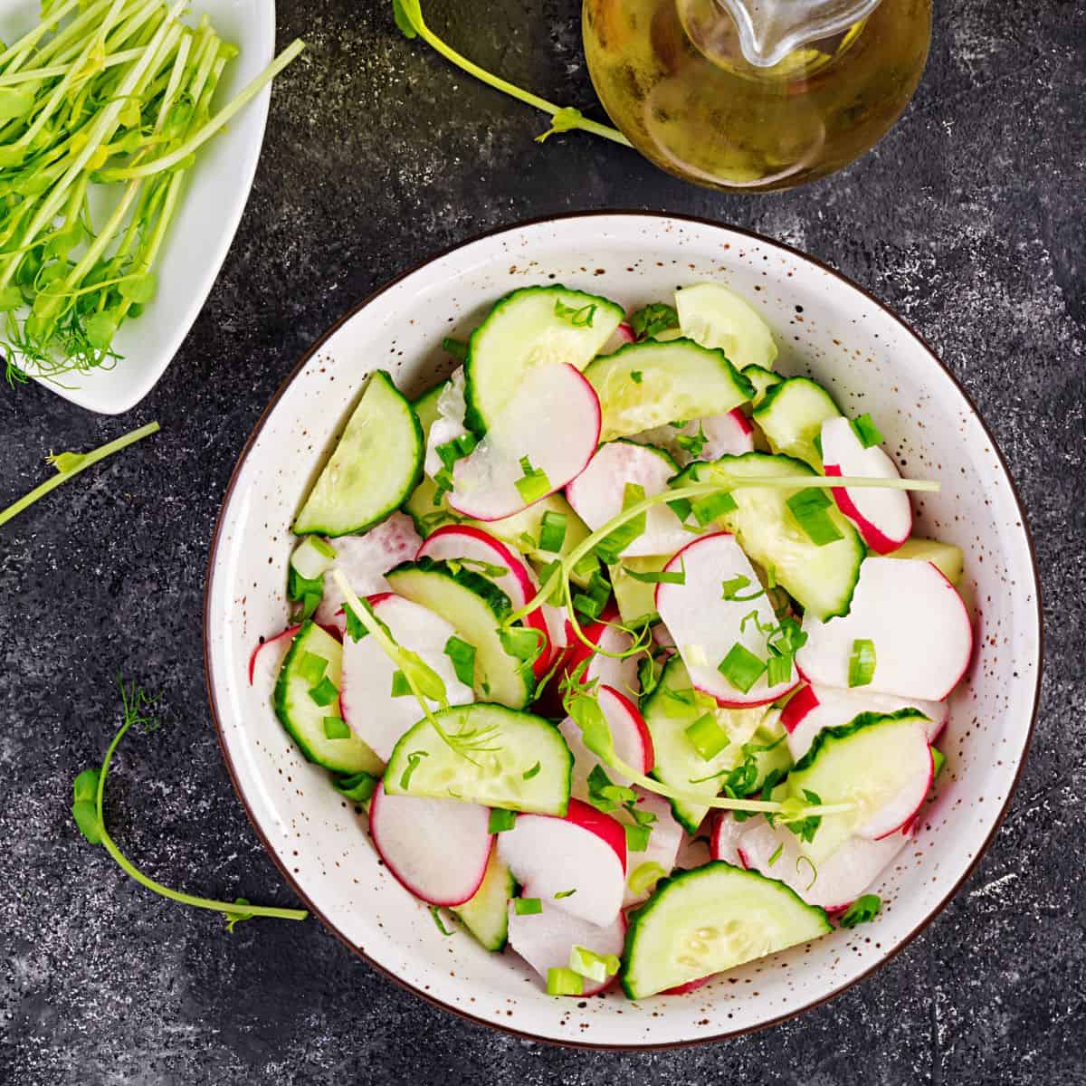 Sliced cucumbers with sliced radishes in a white bowl.