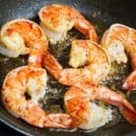 Reheating cooked shrimp in skillet with oil.