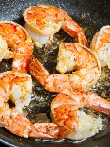 Reheating cooked shrimp in skillet with oil.
