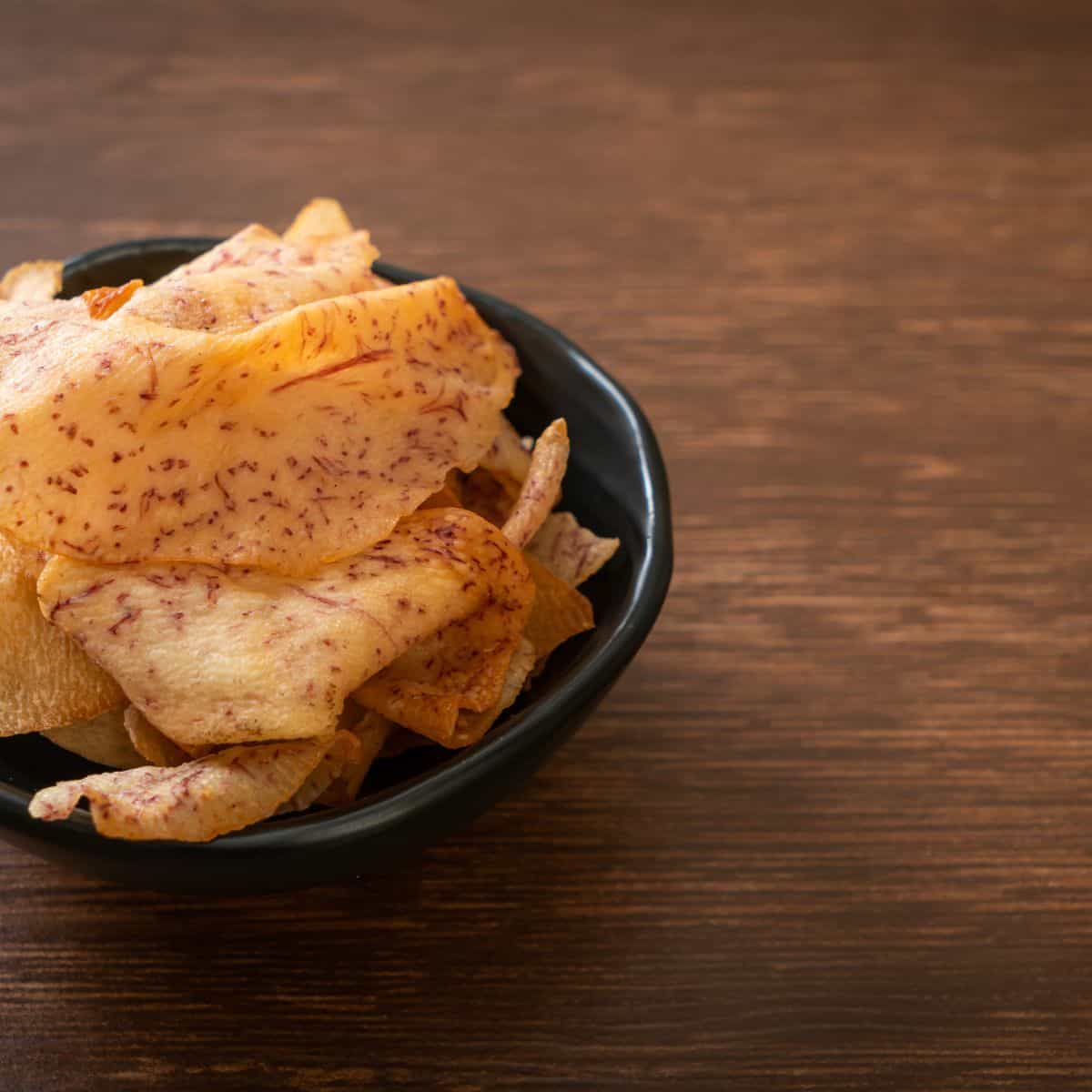 Taro root chips in a black bowl.