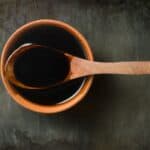 Stir fry sauce in a terracotta bowl with a wooden spoon.