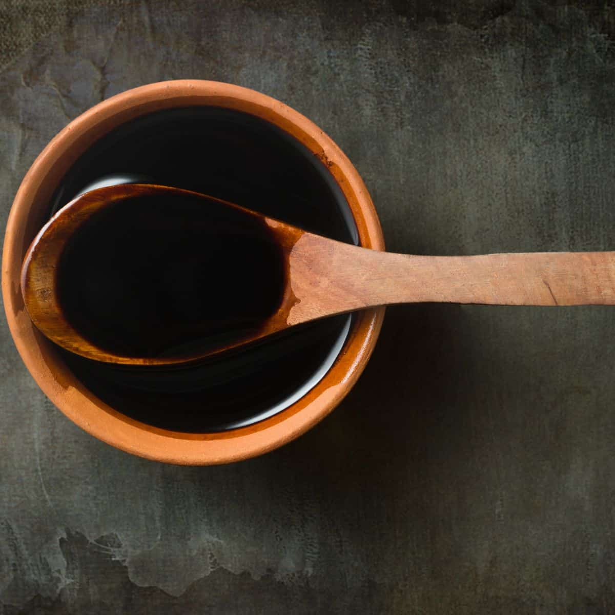 Stir fry sauce in a terracotta bowl with a wooden spoon.