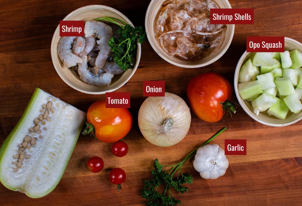Ingredients for sauteed opo squash (shrimp, garlic, tomato, onion, opo squash) on a wooden board.