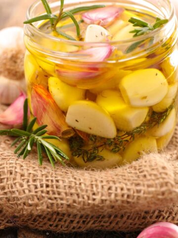 Preserving garlic cloves with olive oil in a jar.