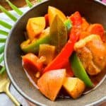 Chicken mechado with vegetables in a brown bowl.