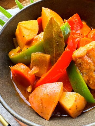 Chicken mechado with vegetables in a brown bowl.