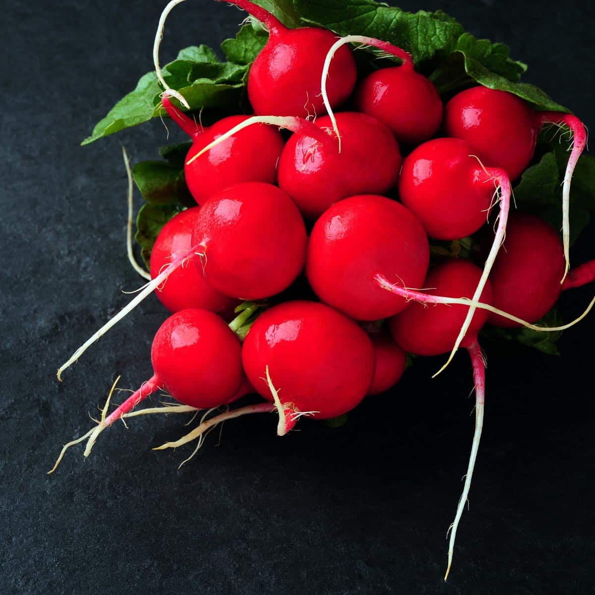 Red radishes on a black countertop.