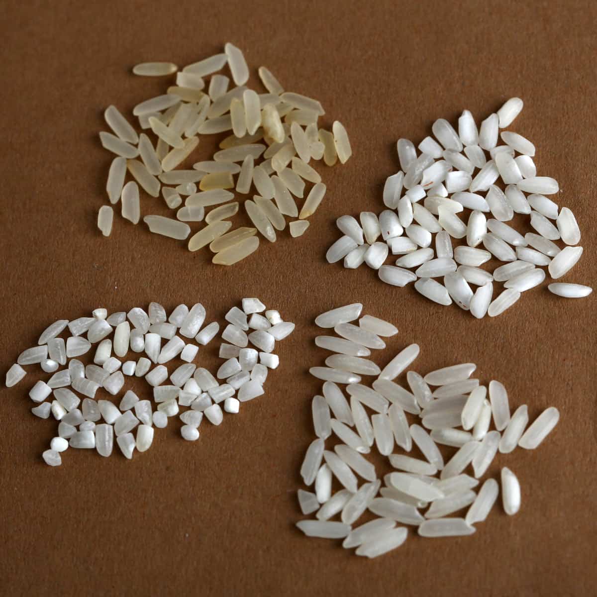 Four types of grains of rice on a brown mat.