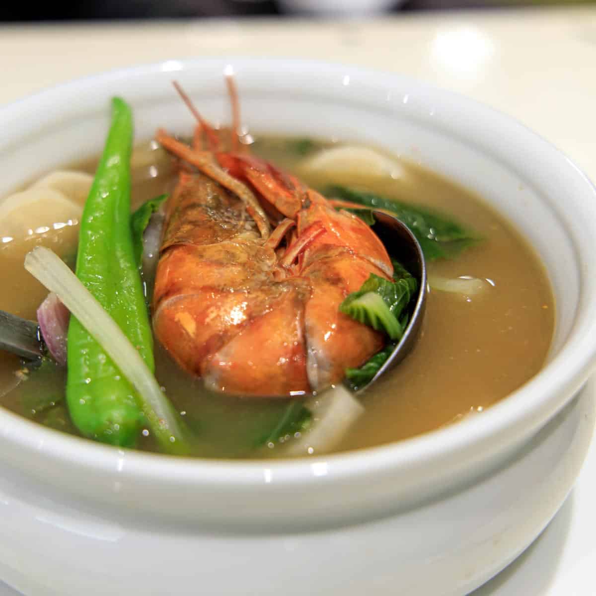 Shrimp sinigang with green chili pepper in a white bowl.