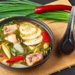 Pork ribs sinigang with vegetables in a black bowl.