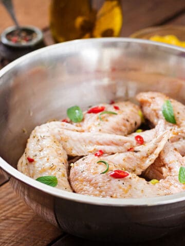 Marinated chicken wings in a stainless steel bowl.
