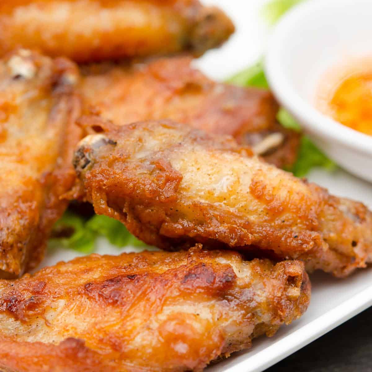 Close up of cooked wings on a white plate.